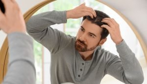 Man examining his hairline in the mirror, considering Nutrafol for Men for hair loss.
