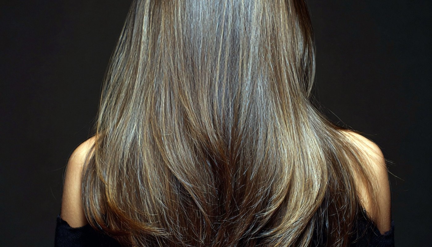 A person with long, shiny brown hair showcasing Nutrafol for Women hair results from the back.